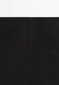 Tissu noir disposé avec une texture lisse ; présente une couture verticale au centre. Le design est simple et uniforme, sans motifs ni embellissements.