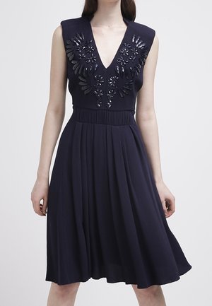 Vestido navy con un profundo escote en V y diseño sin mangas, que presenta bordados florales y lentejuelas en la parte superior, falda acampanada, tela suave.