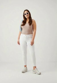 Baltas šauras džinsus, svītrainu topu oranžā un zilā krāsā, baltas saulesbrilles un sudraba sporta apavus. Iekļauts gaiši zils pleca soma.