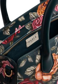 Borsa a mano con motivo floreale, manici neri e zip dorata, che mostra l'etichetta interna con la scritta "FABLE England."