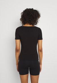 Svart ribbad t-shirt med korta ärmar, med en rak halsringning och en figurnära design, matchad med mörka shorts.