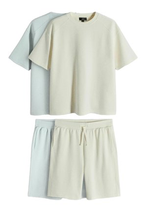 Zwei Sets kurzärmeliger T-Shirts und Shorts mit Kordelzug, eines in Creme und eines in Hellgrau, flach auf weißem Hintergrund ausgelegt.