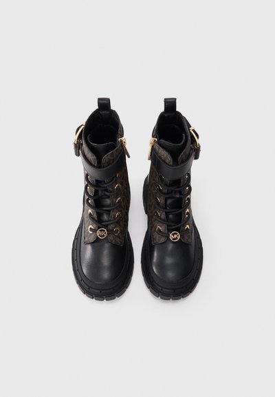 Bottines en cuir noir avec un côté à motifs bruns, quincaillerie dorée, semelle en caoutchouc robuste et fermeture à lacets.