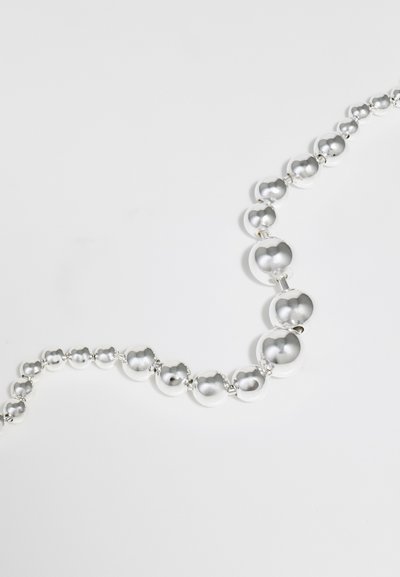 Collier en argent avec une série de perles sphériques de tailles variées, présentant une surface lisse et réfléchissante ainsi qu'un éclat métallique.