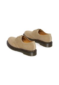 Scarpe in suede beige con profilo basso, punta rotonda e suola in gomma resistente con cuciture gialle lungo il bordo.