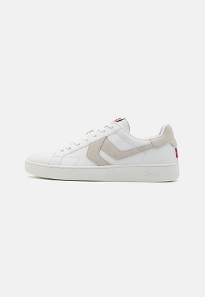Des baskets blanches avec un empiècement en cuir lisse, des accents en suède beige, des lacets plats et une semelle en caoutchouc texturée. Comprend un détail de marque.