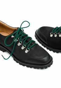 Scarpe in suede nere con suola in gomma, dotate di lacci verdi, occhielli in argento e punta in pelle liscia.