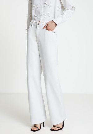 Jeans bianchi a gamba larga in denim con finitura strutturata; presenta una chiusura con bottoni, tasche laterali e un design pulito.