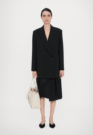 Črn tailoring blazer z ostrimi reverji in enim gumbom, v kombinaciji s tekočo črno krilom. Nosite kviltirano bež torbico. Črne koničaste balerinke.