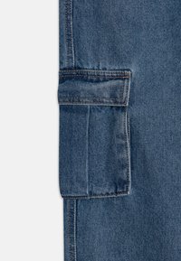 Pantalón cargo de denim con un lavado azul, textura resistente, bolsillo lateral y costuras de contraste a lo largo de las costuras, que muestra un diseño funcional.
