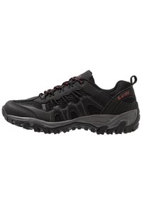 Black athletic shoe made of mesh and synthetic material with a textured surface, featuring red accents, a reinforced toe, and a rugged sole.
