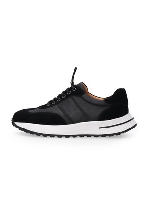 Schwarze Sneaker aus einer Kombination von glattem und Wildleder-Material, mit einer gepolsterten weißen Sohle und schwarzem Schnürverschluss mit silbernem Beschlag.