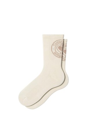Par de calcetines crema de caña media con puños acanalados y un logo redondo con un corazón en la parte superior de la pantorrilla.