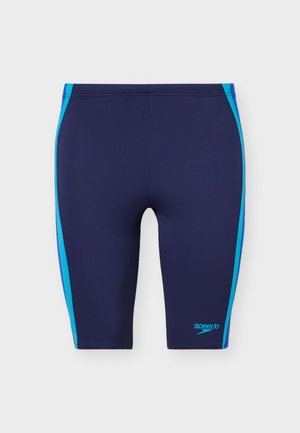 Námořnicky modré plavecké kraťasy typu jammer s světle modrými pruhy na bocích a logem Speedo na levé nohavici, navržené pro závodní plavání.