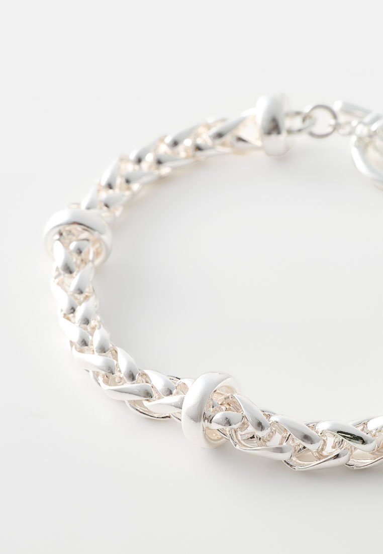 Silberne Kettenarmband mit geflochtenen Gliedern und runden Akzenten, glänzender Textur und sicherem Verschluss. Geeignet für verschiedene Anlässe.