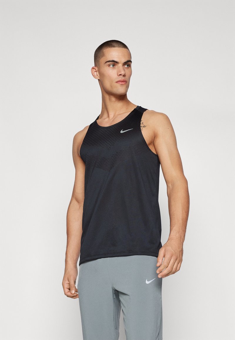 Débardeur de sport noir avec un col rond, présentant un motif texturé sur le devant supérieur et un logo Nike en argent réfléchissant.