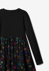 Sukienka z długim rękawem, z czarnym, prążkowanym gorsetem oraz rozkloszowanym, wielokolorowym dołem w serduszka z czerwonymi, zielonymi i niebieskimi akcentami.