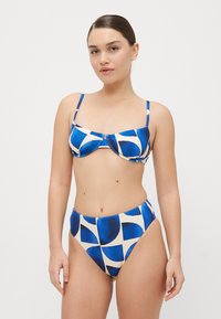 Kék és bézs mintás bikini szett, amely egy merevített bralette topból és magas derekú alsórészből áll, geometrikus mintázattal. Az állítható pántokkal rendelkező top biztosítja a kényelmet.