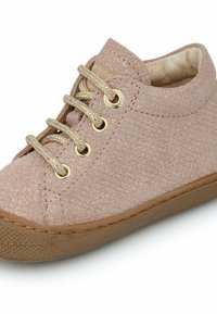 Růžové semišové dětské tenisky s texturovaným povrchem, kulatou špičkou, zlatými nýty a odpovídajícími tkaničkami, umístěné na světle hnědé gumové podrážce.