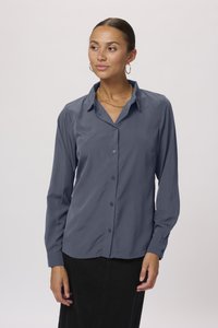 Chemise grise à manches longues avec col, présentant une texture lisse et un design légèrement ajusté. Complétée par des poignets boutonnés.