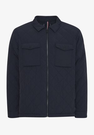 Tengeri kék steppelt dzseki elöl cipzárral, két, fedéllel ellátott mellzsebbel és álló gallérral. Textúrált anyag átlós mintával.