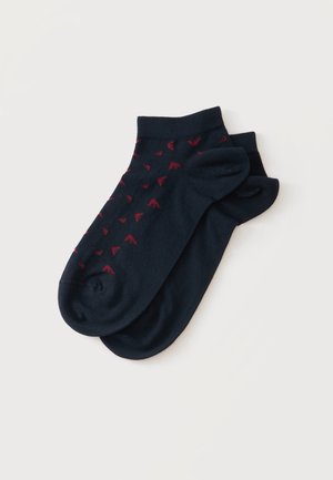 Paire de chaussettes courtes noires avec petits motifs flèche rouges sur une chaussette, présentée sur fond blanc.