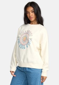 Crème-kleurige sweatshirt met een ronde, meerkleurige zonafbeelding en tekst "BILLABONG WORLD TOUR" in het blauw. Gemaakt van katoen en met een ontspannen pasvorm.