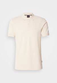 Polo beige à manches courtes avec col, patte de boutonnage à deux boutons et petit logo sur la poitrine et l'étiquette du cou.