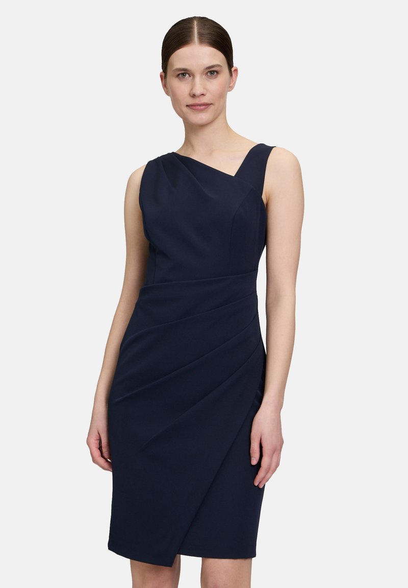 Robe asymétrique bleu marine en tissu lisse, avec un drapé diagonal, une silhouette élégante et une coupe au genou.