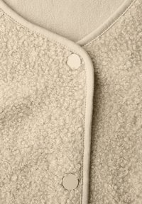 Roomkleurige, gestructureerde fleece stof met twee matte drukkers en een gladde randafwerking.