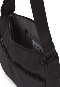 Bolso de hombro de tela negra con múltiples compartimentos con cremallera, correa ajustable y textura suave. El interior cuenta con bolsillos organizadores.
