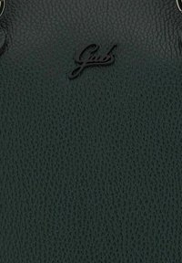 Sort tekstureret læder med lille signatur metallogo "Gabs" fastgjort nær den øverste midte.