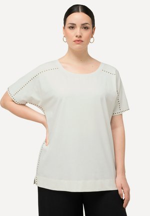 Camiseta blanca de manga corta con acentos laterales de tachuelas doradas, cuello redondo y un corte relajado. Fabricada en un tejido ligero.