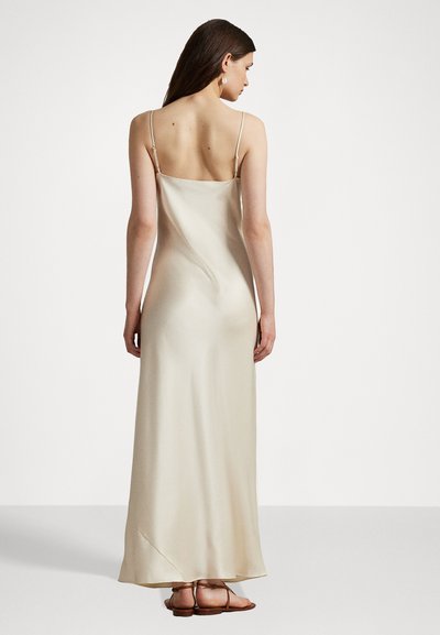 Satin strømpkjole i lys beige med tynde stropper, rygfri design og en flydende silhuet. Har subtil drapering og glat tekstur.