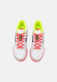 Zapatillas deportivas blancas con acentos verde neón, cordones rosas y marca en negro. Presentan texturas sintéticas y de ante suaves.