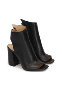 Botas de tobillo de tacón abierto de cuero negro con tacón cuadrado, detalle recortado y textura suave. Incluye una cremallera para facilitar su uso.