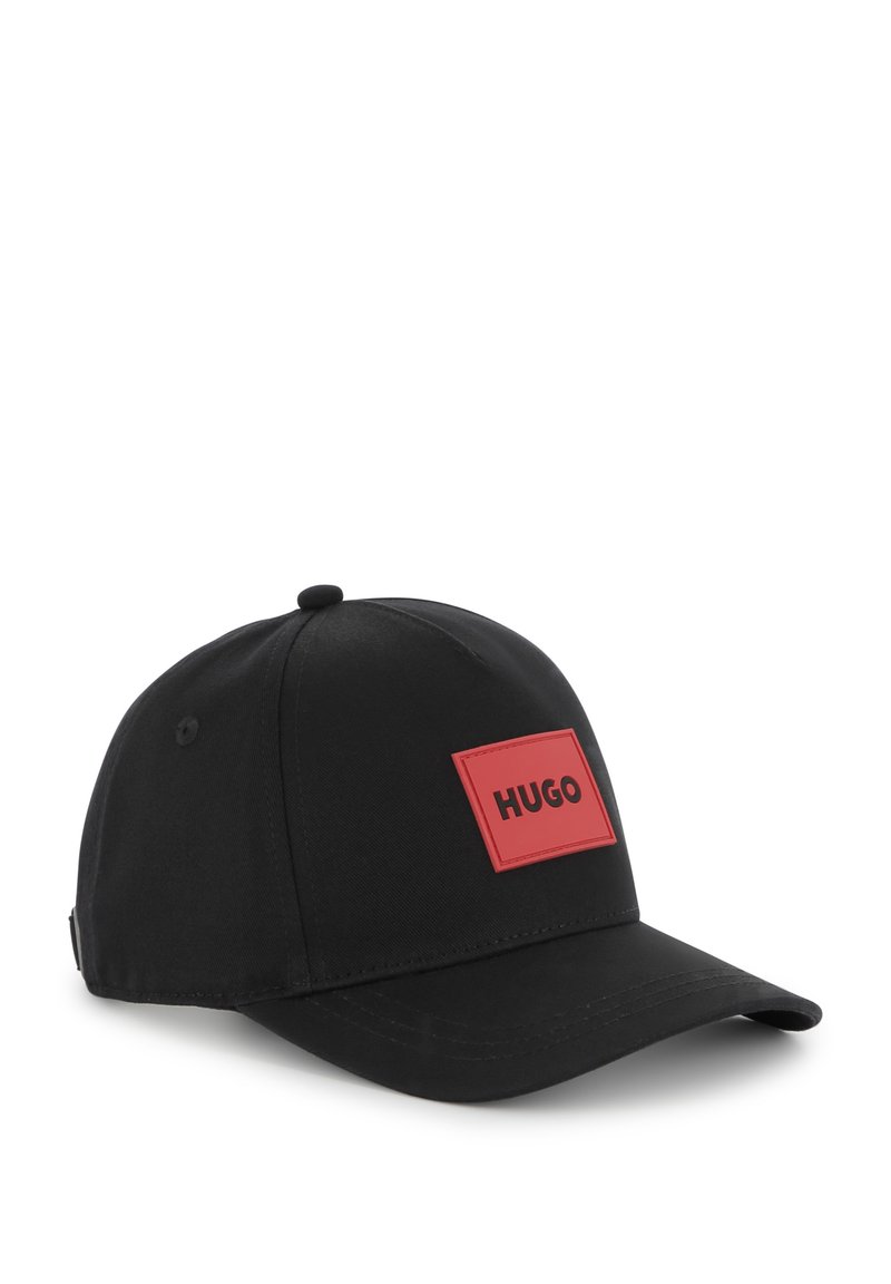 Casquette de baseball noire en tissu, avec un patch logo rectangulaire rouge portant l'inscription "HUGO" en noir, et une visière courbée pour l'ombre.