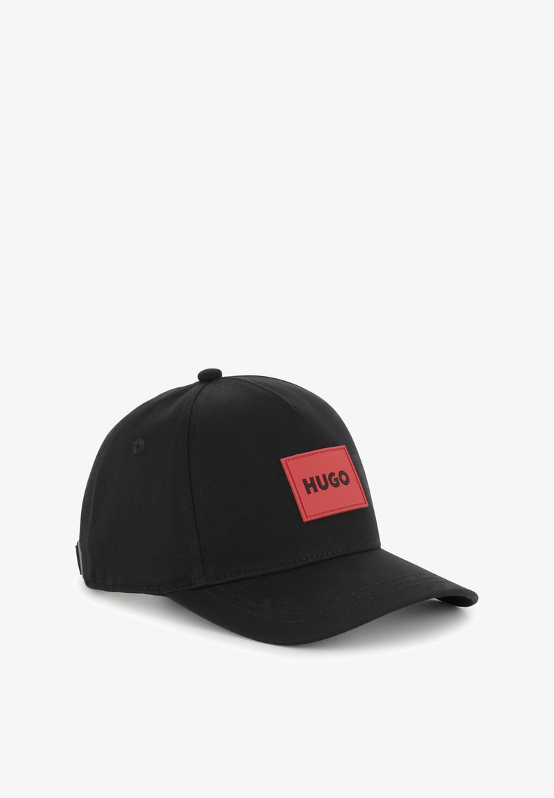 Casquette de baseball noire en tissu, avec un patch logo rectangulaire rouge portant l'inscription "HUGO" en noir, et une visière courbée pour l'ombre.