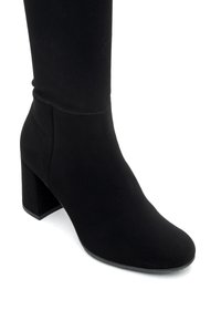 Botín de tela negra hasta el tobillo con un tacón cuadrado, punta redonda y textura suave. El diseño presenta costuras mínimas para un aspecto elegante.