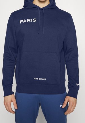 Sudadera de color azul marino con un bolsillo tipo canguro, con texto en blanco que dice "PARIS" y "SAINT-GERMAIN". Incluye puños acanalados y un detalle del Swoosh de Nike.