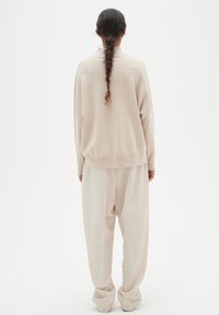 Beige oversized sweater and loose-fitting trousers, both crafted from soft fabric, featuring a relaxed silhouette and subtle texture details.