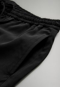 Svarta idrottsshorts med strukturerad tyg, med elastisk midja och sidofickor. Designade med en avslappnad, sportig stil.