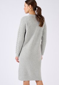 Abito lavorato a maglia grigio chiaro con texture a coste e dettagli a trecce sulle maniche, dalla silhouette morbida e dal design al ginocchio.