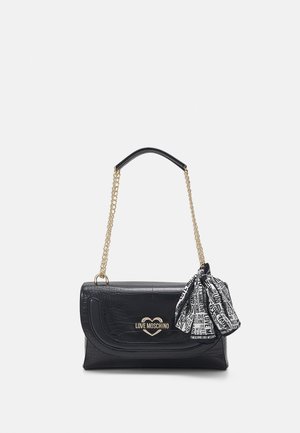 Bolso negro con textura de cocodrilo, correa de cadena dorada, logo dorado de Love Moschino y un lazo de tela blanco y negro con la marca, adherido.