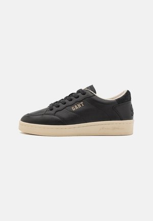 Schwarze Leder-Sneaker mit beiger Gummisohle, auf der Seite mit Markenlogo, runder Zehenpartie und strukturiertem Rückenteil. Schnürdesign.