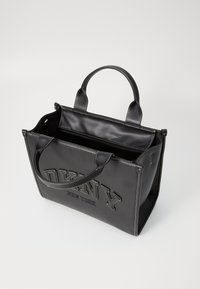Zwarte leren tote bag met reliëflogo, bovenhandvatten, open ontwerp, contrasterende stiksels en twee compartimenten aan de binnenkant.