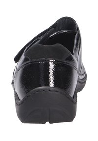 Zwarte, glanzende leren schoen met een lage hak en klittenbandsluiting, met een gladde textuur en een afgerond ontwerp zichtbaar vanuit een achteraanzicht.