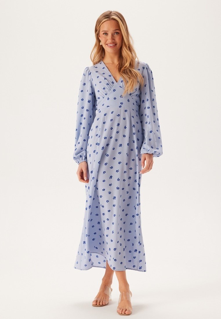 Lichtblauw bloemenjurk met lange pofmouwen en een v-halslijn, met een vloeiende silhoutte en verspreide donkerblauwe bloempatronen.
