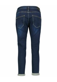Dark blue denim jeans with a tapered fit. Two back pockets with yellow stitching, cuffs rolled up, and a leather brand patch on the waistband.