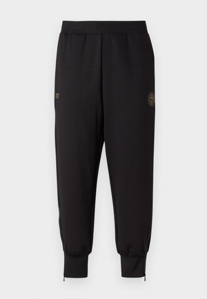Svarta joggingbyxor gjorda av sträckbart material, med en guld-logotypaccent, elastisk midja, dragkedjeanpassade ankelflärpar och avsmalnande passform.